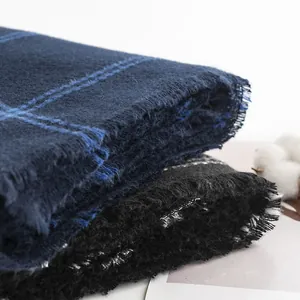 Close-up detail of soft plaid scarf fabric texture with fringed edges in navy blue