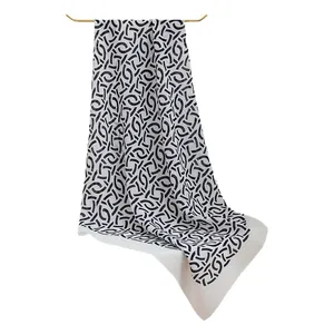 Élégant foulard en soie blanc à motif géométrique noir suspendu à une barre dorée