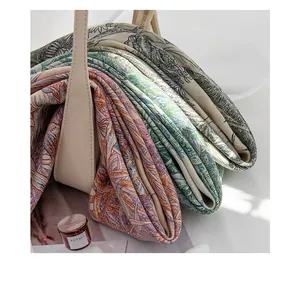 Close-up of luxury silk wool scarves with intricate botanical embroidery in a bag