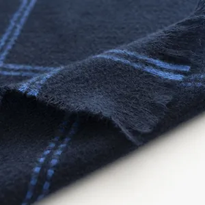 Close-up of soft navy blue checkered scarf texture with elegant fringed edges.