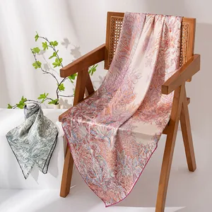 Elegante bufanda cuadrada de seda de lujo con motivo floral en una silla de madera