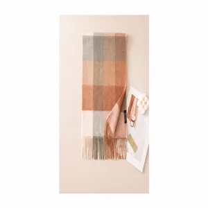 Detail of 100% cashmere plaid scarf in warm red and camel tones with fringe detail.