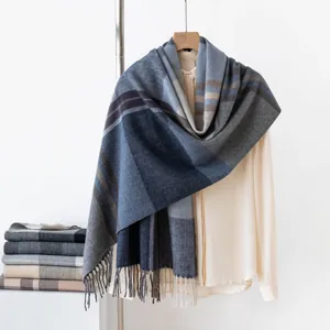 Detailed view of a thick blue plaid winter scarf with decorative fringe accents