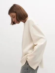 Profil d'un mannequin portant un pull en maille de coton beige surdimensionné et décontracté.