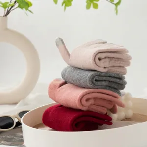 Stapel van vier paar dikke winterhandschoenen van 100% wol voor dames in diverse zachte kleuren.