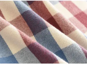Detailopname van de zachte geruite stoftextuur in rood en blauw voor een warme wintersjaal