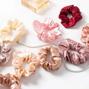 Assortment of elegant satin silk scrunchies displayed with pearl necklace and perfume