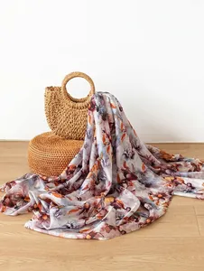 Dettaglio di un elegante foulard in seta di gelso a fiori su borsa di paglia