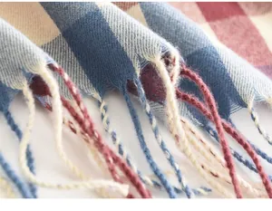 Detailopname van de zachte textuur en kwastjes van een blauw-crème geruite wintersjaal.