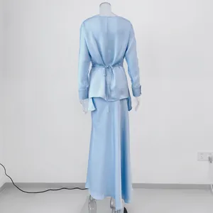 Back view detail of an elegant light blue satin long sleeve top and maxi skirt set