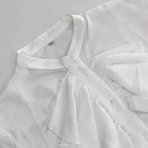 Primer plano de blusa blanca con volantes de estilo francés y botones transparentes