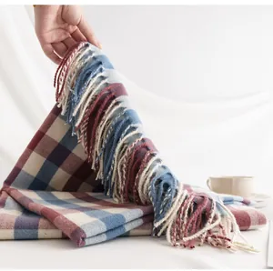 Detailopname van een zachte wintersjaal met elegante kwastjes en een rood-blauw geruit patroon