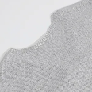 Detailed close-up view of the fine knit texture and ribbed neckline on a light grey sweater