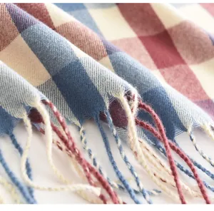 Close-up van een zachte geruite wintersjaal met decoratieve kwastjes en franjes aan de rand