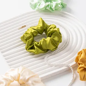 Macro view of silk scrunchies in various colors on a white textured tray.