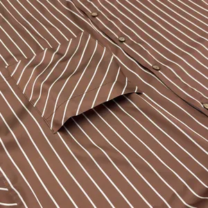 Détail en gros plan d'un tissu satiné à rayures marron et blanc avec des boutons