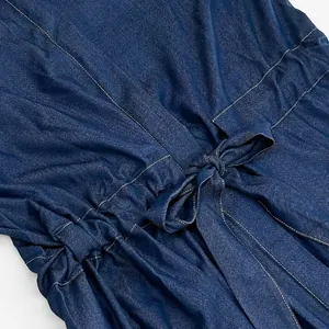 Macro shot of the adjustable drawstring waist with a bow tie on a blue denim dress