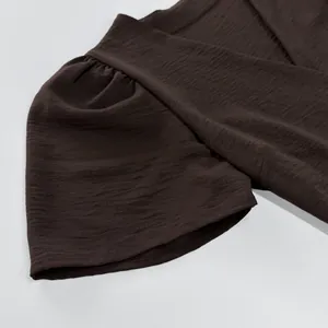 Close-up detail of textured chocolate brown fabric and elegant puff sleeve summer dress