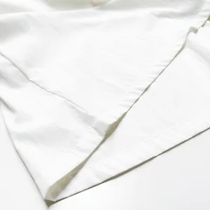 Gros plan détaillé montrant les coutures de qualité d'un ensemble de détente en coton blanc