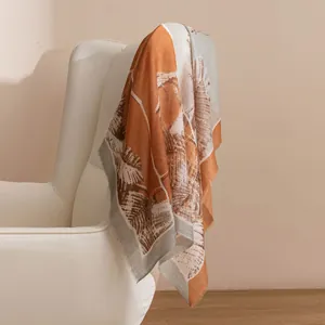 Élégante écharpe en cachemire 100% avec imprimé de feuilles tropicales sur une chaise