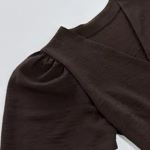 Close-up of textured fabric and sleeve detail on a chocolate brown elegant dress