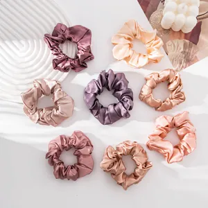 Macro detail view of eight elegant silk scrunchies in various Morandi solid colors.