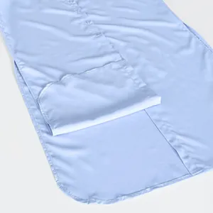 Macro detail of a light blue long shirt dress showing the curved hem and button placket