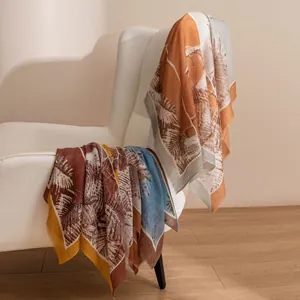 Écharpe élégante en cachemire fin à imprimé tropical drapée sur un fauteuil blanc