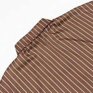 Gros plan montrant le col et la texture du tissu d'une chemise en satin à rayures marron