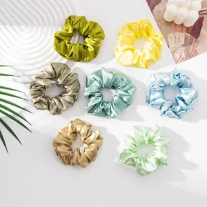 Close-up detail of large silk satin scrunchies showing glossy textures and diverse colors