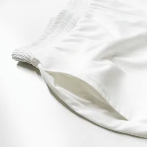 Détail d'un short de détente blanc minimaliste avec taille élastique et poche latérale.