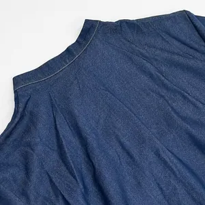Detailed close-up showing the neckline stitching and fabric texture of this blue denim dress.