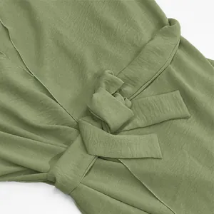 Close-up detail of the waist tie knot on a sage green elegant cardigan dress.
