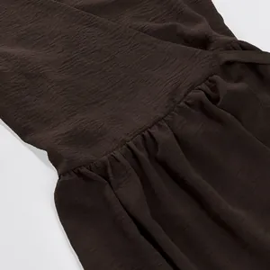 Detailed view of brown textured fabric and gathered waist on an elegant maxi dress