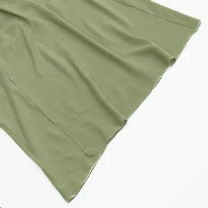 Close-up of olive green breathable fabric texture and hem detail on a long dress