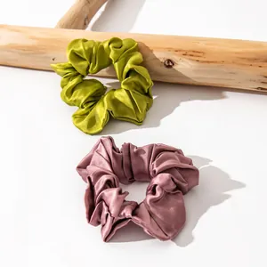 Detailed view of olive green and mauve silk scrunchies with elegant satin luster