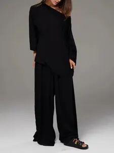 Détail d'un ensemble d'intérieur noir français chic avec haut asymétrique et pantalon large