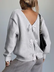Close-up detail of a white V-back knit sweater featuring three elegant satin bow decorations.
