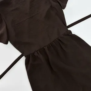 Detail view of dark coffee short-sleeved dress showing waistline and textured fabric