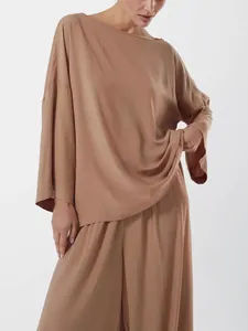 Détail de l'ensemble de détente marron avec haut oversize et pantalon large au fini satiné