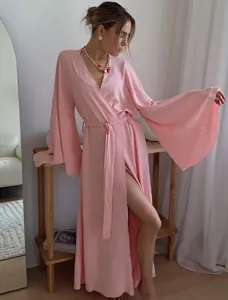Elegant long pink wrap dress with flared sleeves shown in a lifestyle setting
