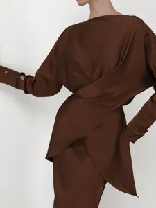 Close-up detail of elegant chocolate brown satin evening dress with draped wrap design