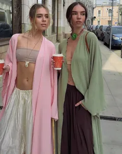 Elegant long open-front cardigans in pink and sage green shown in a street style