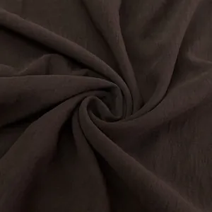 Detailed close-up of dark brown textured fabric showing elegant drape and high-quality fine weave.