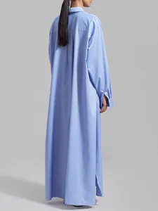 Elegant back view of a long light blue French-style shirt dress with side slits.
