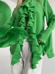 Detalle de una elegante blusa verde de manga larga con volantes frontales y puños de campana.