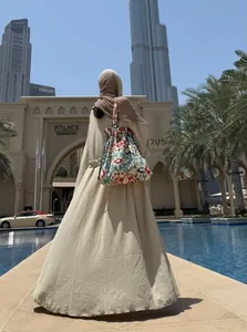 Elegant beige long cardigan dress for women styled with a patterned tote bag in a city setting