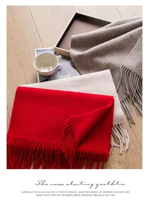 Gros plan d'écharpes en laine unie avec pompons en rouge, beige et moka