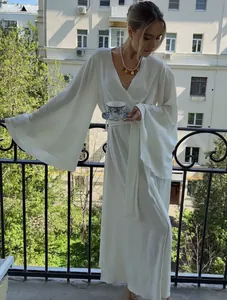 Elegant white long dress with wide bell sleeves shown in a balcony setting