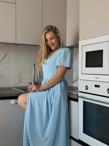 Elegant light blue short sleeve maxi dress worn by model in a modern kitchen setting